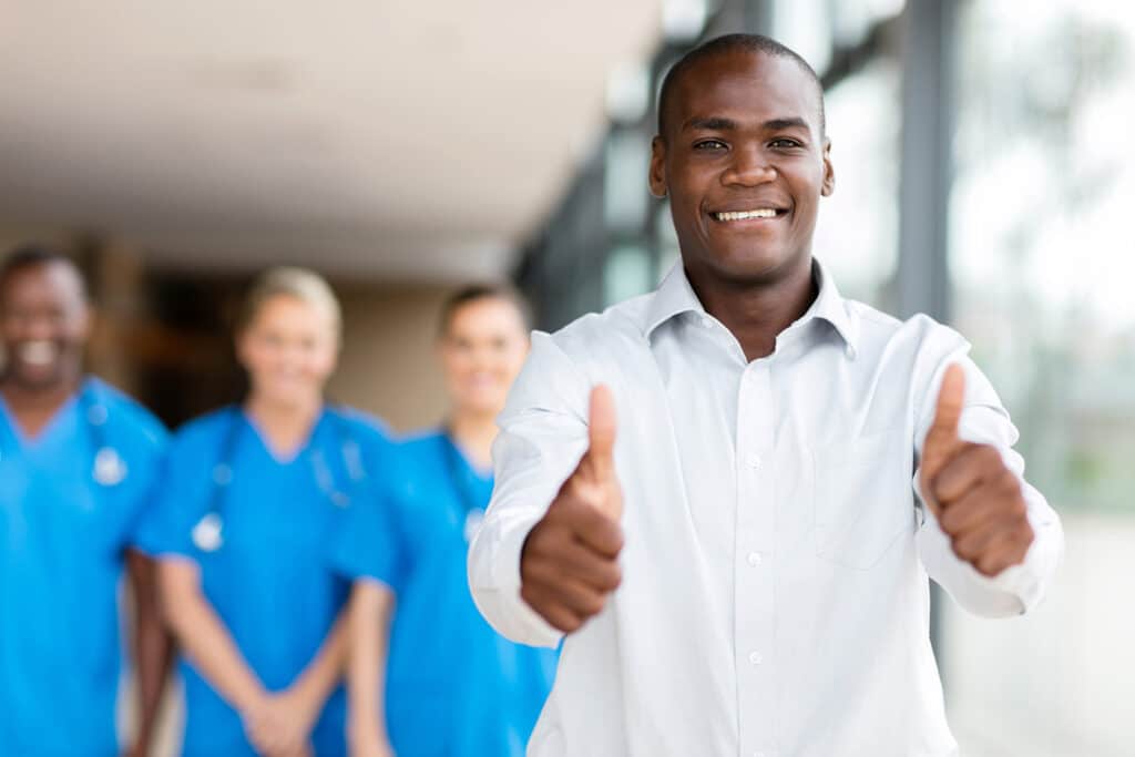happy man giving thumbs up in front of medical group