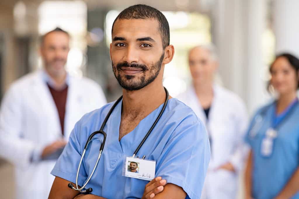 Portrait of smiling male nurse in uniform and stethoscope looking at camera.